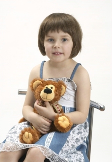爱上坐在椅子上抱着布娃娃的快乐孩子图片